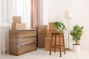 Boxes, lamp and chest of drawers wrapped in stretch film indoors