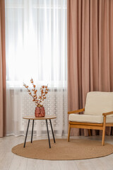 Living room with pastel window curtains, wooden table and armchair