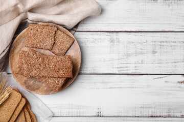 Rye crispbreads and rusks on white wooden table, flat lay. Space for text