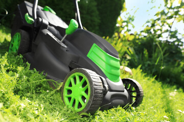 Lawn mower on green grass in garden