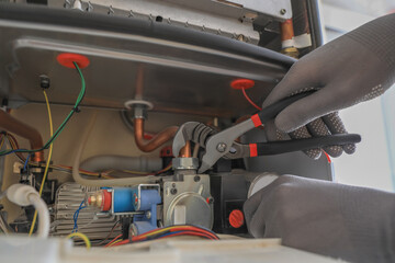 Man repairing gas boiler with waterpump plier, closeup