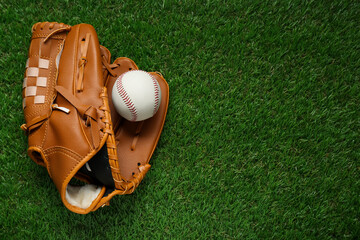 Catcher's mitt and baseball ball on green grass, top view with space for text. Sports game