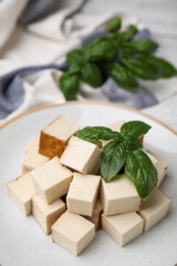 Plate with delicious smoked tofu and basil, closeup