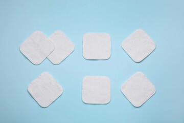 Many cotton pads on light blue background, flat lay