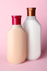 Bottles of shampoo on pale pink background