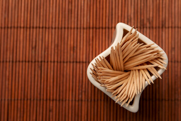 Holder with many toothpicks on bamboo mat, top view. Space for text
