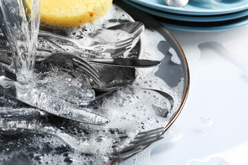 Pouring water onto silverware in foam, closeup