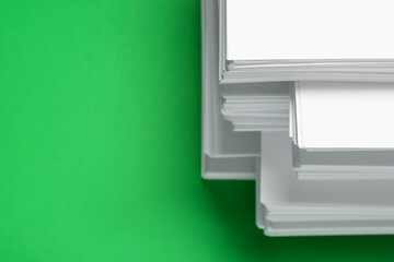 Stack of white paper on green background, closeup. Space for text