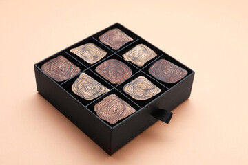 Box of tasty chocolate candies on beige background, closeup