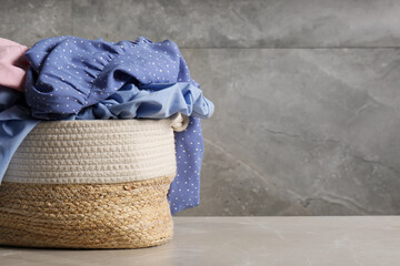 Laundry basket with clothes near grey wall. Space for text