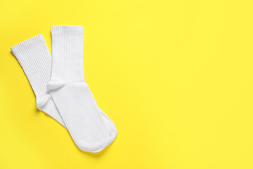 Pair of white socks on yellow background, flat lay. Space for text