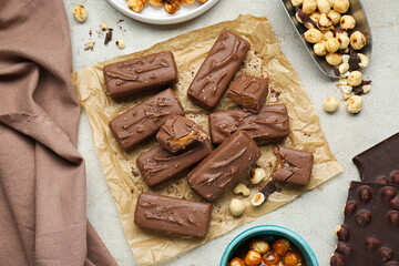 Delicious chocolate candy bars and nuts on light table, flat lay