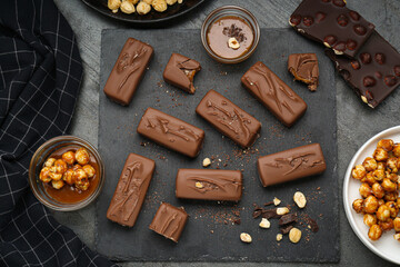 Delicious chocolate candy bars with caramel and nuts on grey table, flat lay