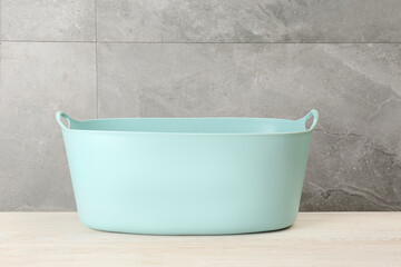 Empty plastic laundry basket near grey wall