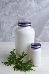 Medical bottles and arugula on white wooden table