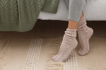 Woman wearing warm knitted socks at home, closeup. Space for text