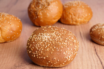 Fresh buns with sesame seeds on wooden table