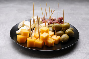 Toothpick appetizers. Pieces of cheese, sausage and olives on light grey table - obrazy, fototapety, plakaty