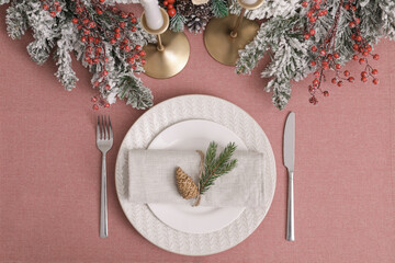 Obraz na płótnie Canvas Festive place setting with beautiful dishware, cutlery and cone for Christmas dinner on pink tablecloth, flat lay