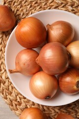Many ripe onions on wooden table, flat lay