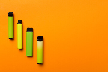 Disposable electronic cigarettes on color background, top view
