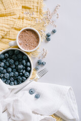 Blueberries and Hot Chocolate Flat Lay on Yellow and White cloth.