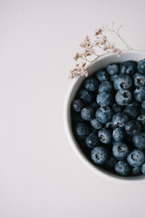 Blueberry berries in bowl on beide background