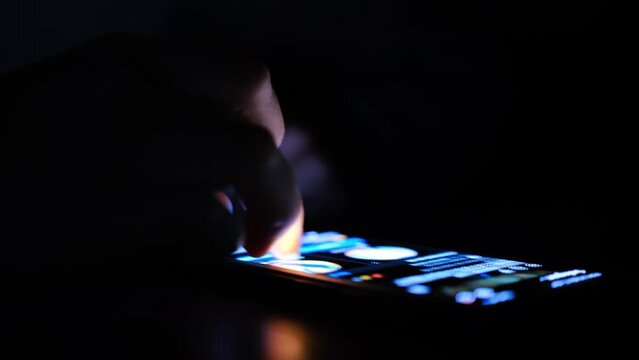 Close up of man finger using and touching on smartphone screen with reflection and black background in the darkness. Social network surfing, instagram or facebook or tiktok