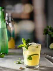Refreshing yellow alcoholic iced lemon lime cocktail drink in glass on the bar counter of the nightclub.