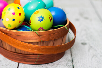Basket with painted colorful easter eggs on wooden table