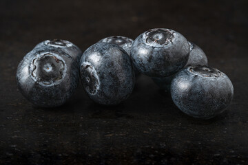 seven blueberries on black stone