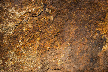 Close up of a solid granite rock in a variety of yellow and brown shades of color.