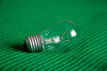 An incandescent lamp lies on a green knitted fabric