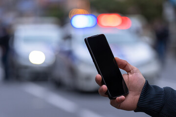 Holding a phone in front of police cars © Daniel
