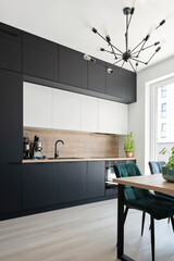 Modern kitchen in contemporary interior. Kitchen furniture in black color with table and chairs....