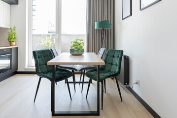 Wooden modern table with chairs in dining room and kitchen with window.