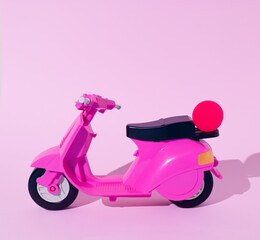 Fototapeta na wymiar Pink moped toy with small ball isolated on a pastel pink background. Concept of travel, fun, transport, holiday.