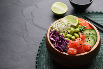 Delicious poke bowl with vegetables, fish and edamame beans on black table, space for text
