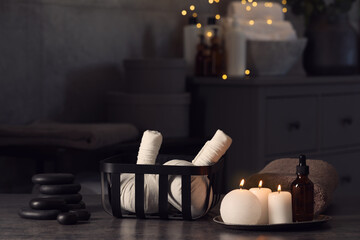Fototapeta na wymiar Herbal massage bags, burning candles and stones on grey table. Spa products