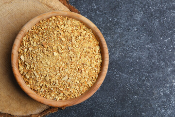 Bowl of dried orange zest seasoning on grey table, top view. Space for text
