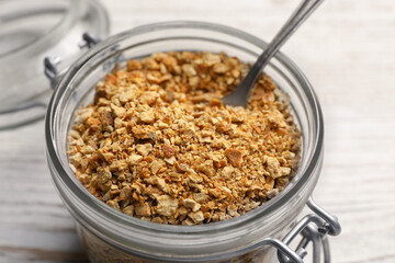 Jar of dried orange zest seasoning on white wooden table, closeup