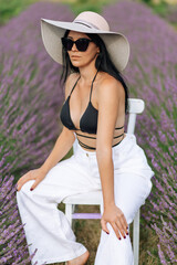 fashion outdoor photo of beautiful woman with dark hair posing in bloomig lavender field on sunset