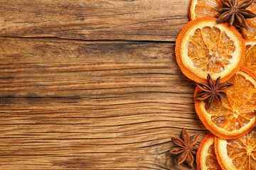 Dry orange slices and anise stars on wooden table, flat lay with space for text