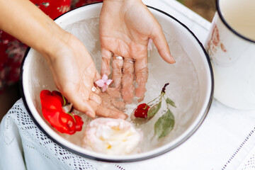 Obraz na płótnie Canvas closeup view of woman soaking her hands and in dish with water and flowers on. Spa treatment and product for female and hand spa. orchid flowers in ceramic bowl.