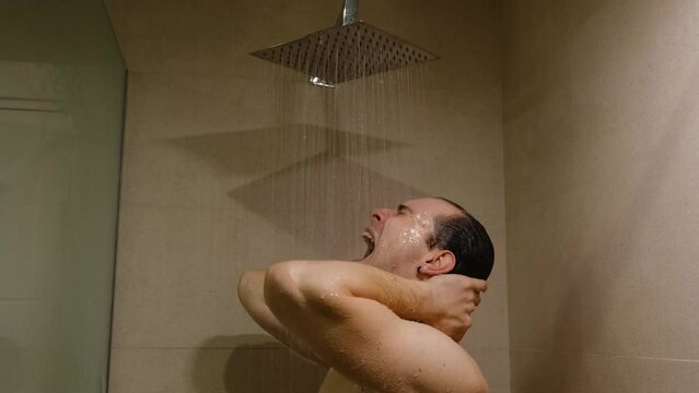 An upset angry man in a shower screaming and learning against a glass. Concept of depression and anger due to the stress, Shower as a place for emotional discharge.