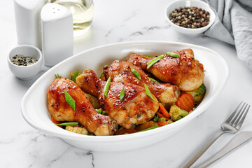 Roasted Baked chicken legs drumsticks with vegetables on baking dish on the table. Meal, dinner diet concept, diet.