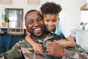 Portrait of happy african american father wearing military uniform and his son embracing