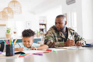Happy african american father wearing military uniform and his son working and doing homework