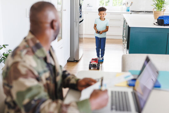 Happy african american father wearing military uniform and his son working and doing playing