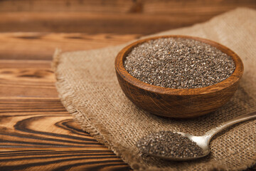 Chia seeds in bowl and spoons on brown wood texture. Diet food. Superfood. Healthy food. Space for text, copy space